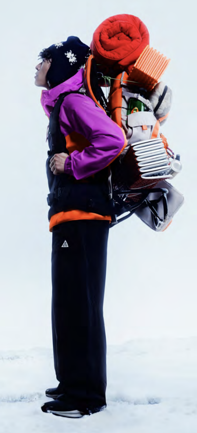 Hiker in a snowy landscape wearing Nike ACG gear with a large backpack